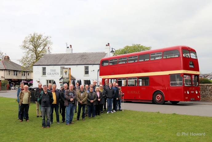A group of people standing in front of a red double decker bus

Description automatically generated
