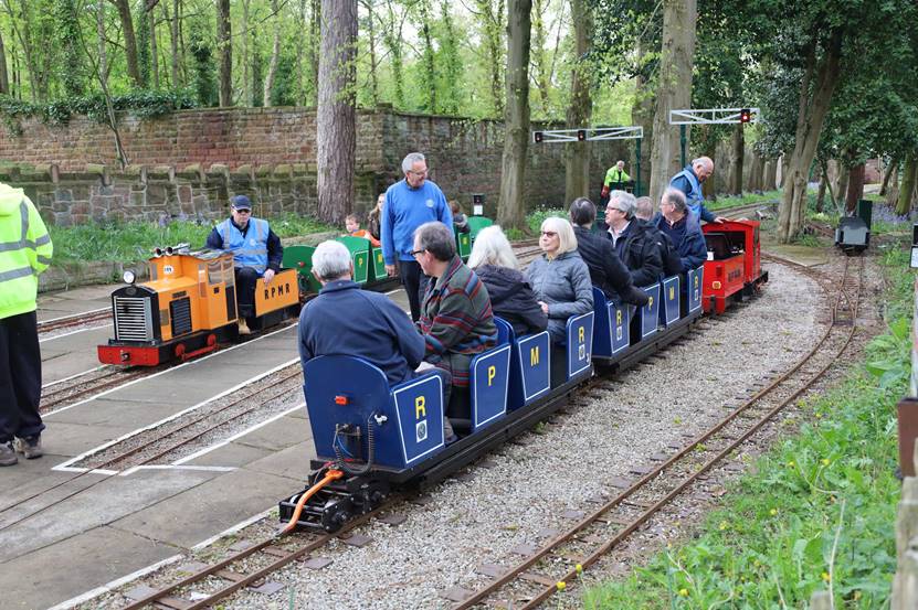 A group of people riding on a small train

Description automatically generated with low confidence